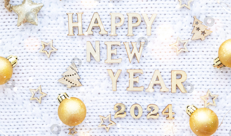 Скачать Деревянные буквы "С Новым годом" и цифры "2024" на уютном праздничном белом вязаном фоне с пайетками, звездами, огоньками гирлянд. Поздравления, открытка. Календарь, обложка фотосток Ozero