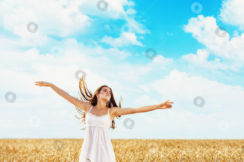 Скачать Молодая девушка подняла руки в лучах солнечного света на фоне поля со спелой пшеницей. Концепция свободы фотосток Ozero