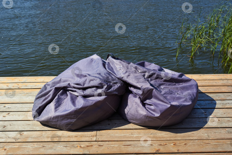 Скачать На деревянном полу лежат две серые сумки для сидения фотосток Ozero