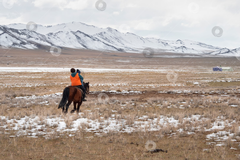 Скачать Двое детей верхом на лошади, вид сзади. Юрта на заснеженном плато, кочевая жизнь в Монголии. Широкий простор. фотосток Ozero