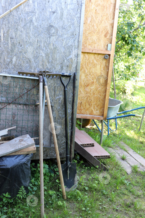 Скачать Садовый инвентарь: лопата, тяпка и грабли у стены сарая фотосток Ozero