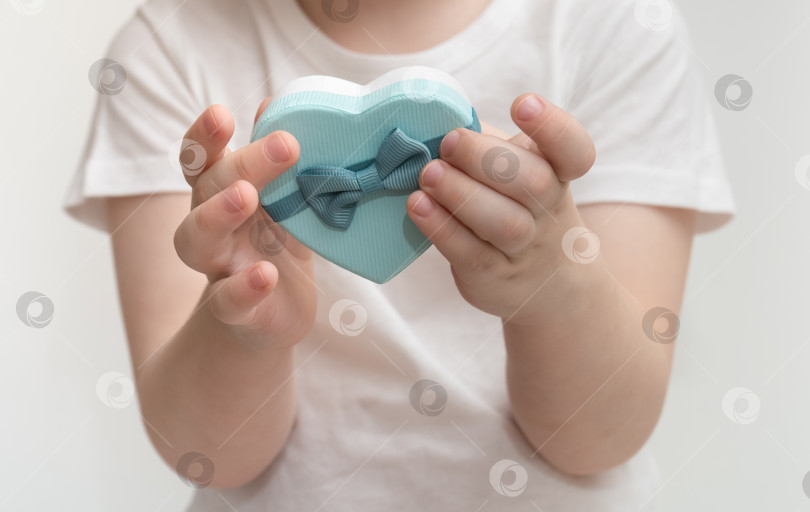 Скачать Ребенок держит в руках подарочную коробку в форме сердца фотосток Ozero