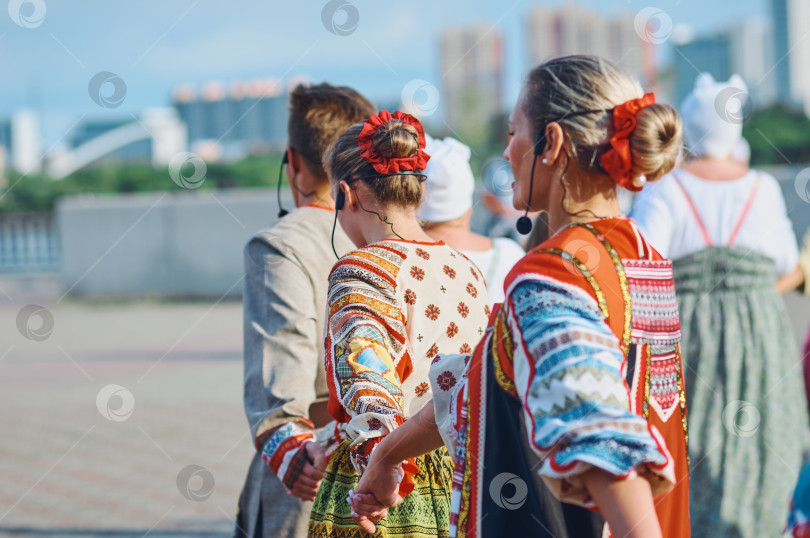 Скачать БЛАГОВЕЩЕНСК, РОССИЯ - 15 июля 2023 года: Выступление творческой группы в русских народных костюмах на набережной. Ансамбль песни и пляски выстраивается в шеренгу и хором исполняет русскую народную песню фотосток Ozero