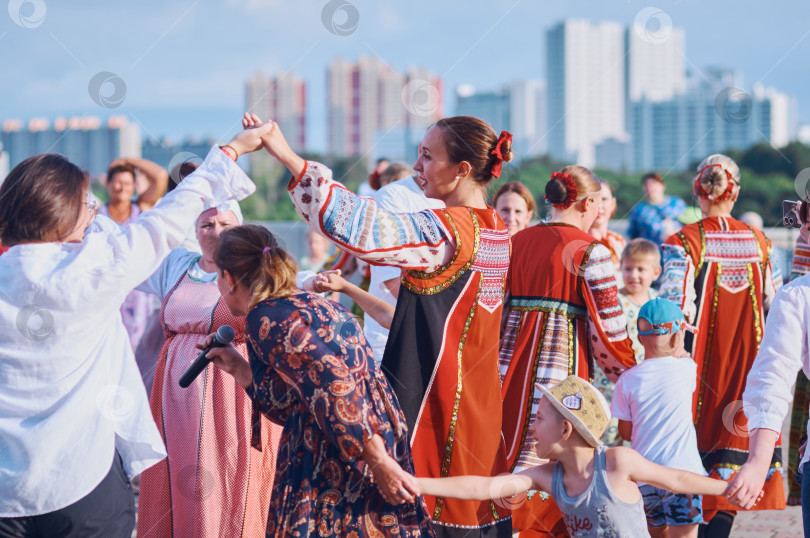 Скачать БЛАГОВЕЩЕНСК, РОССИЯ - 15 июля 2023 года: Выступление творческой группы в русских народных костюмах на набережной. Ансамбль песни и пляски танцует и поет в хороводе вместе со зрителями фотосток Ozero