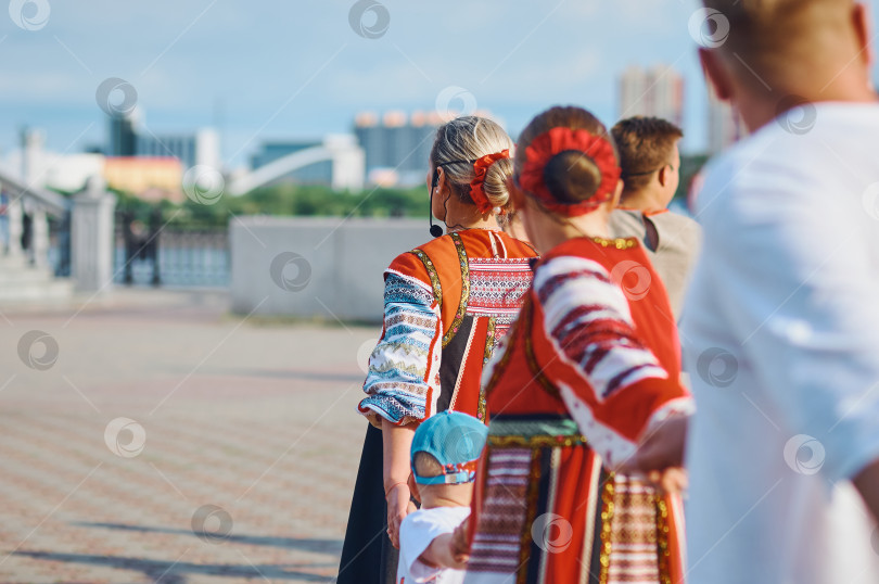 Скачать Фольклорный ансамбль водит хоровод на набережной. Зрители танцуют вместе с танцовщицами в национальных костюмах. Яркий солнечный свет. Концепция: Летние каникулы и фестивали по всему миру. фотосток Ozero