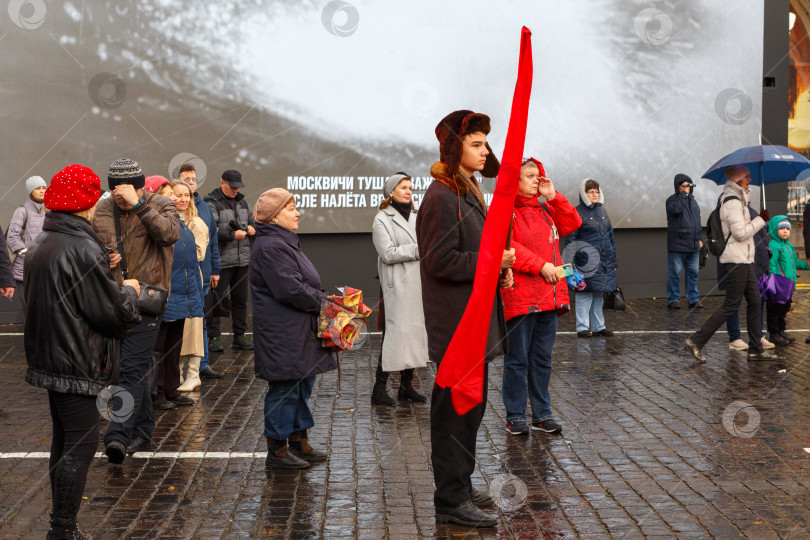 Скачать Москва, Россия - Ноябрь 07,2023: Юноша с красным знаменем в одежде 40-х годов прошлого века фотосток Ozero