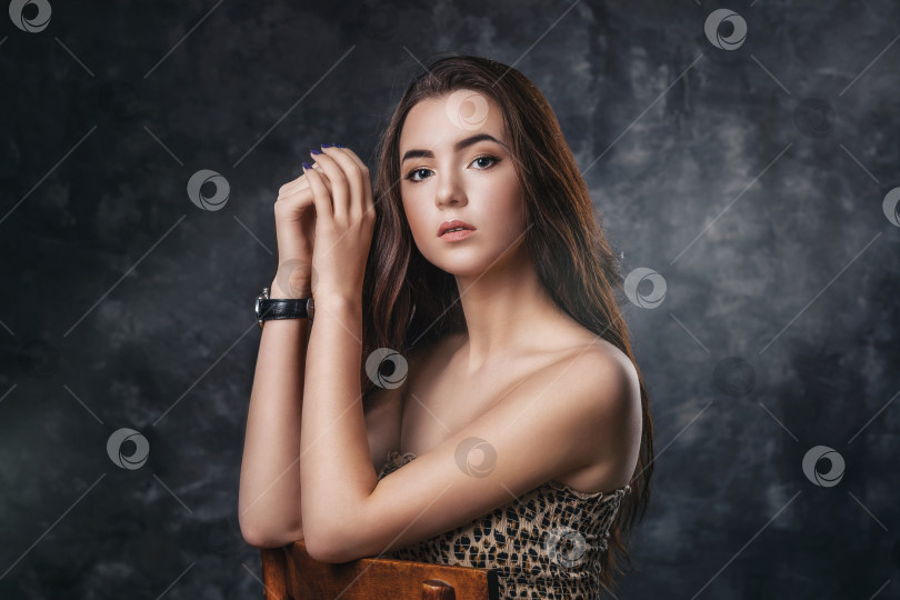 Скачать Портрет молодой красивой девушки, позирующей на деревянном стуле у абстрактной стены фотосток Ozero