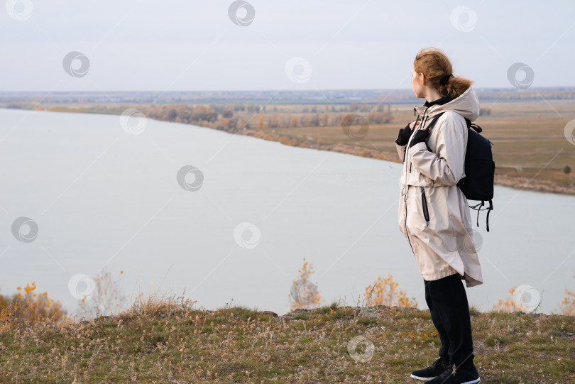 Скачать Молодая девушка стоит на высоком берегу и смотрит на прекрасную природу фотосток Ozero