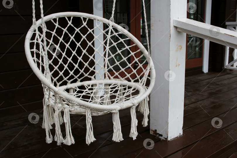 Скачать белое подвесное кресло-качалка на веранде. фотосток Ozero