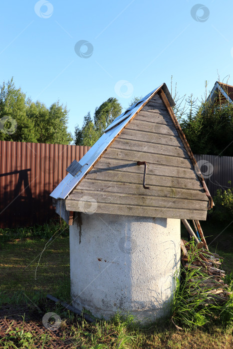 Скачать Круглый каменный деревенский колодец с деревянной крышей - вид сбоку фотосток Ozero
