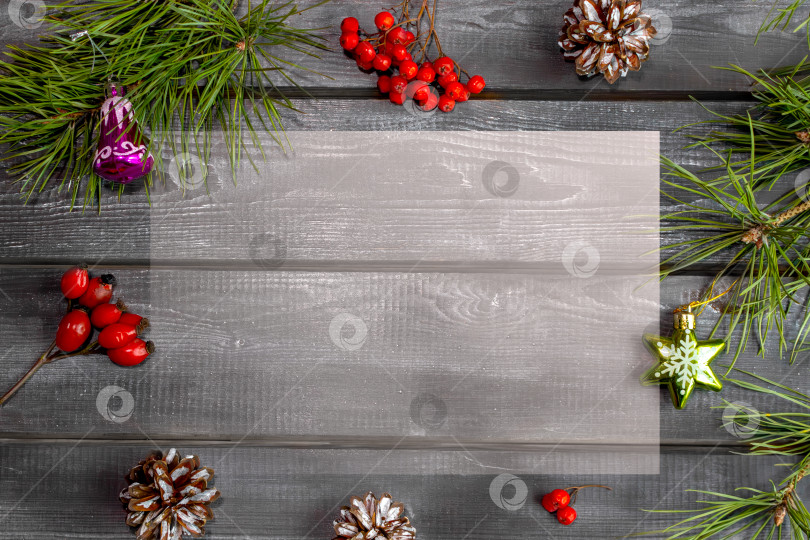 Скачать Деревянный рождественский фон с натуральными сосновыми иголками, красными ягодами, шишками и елочными игрушками. Рамка, открытка фотосток Ozero