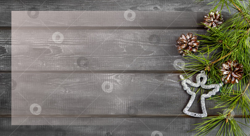 Скачать Деревянный рождественский фон с натуральными сосновыми иголками, шишками и серебряным ангелом. Рамка, баннер, открытка фотосток Ozero