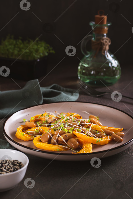 Скачать Вегетарианский полезный салат с запеченной тыквой, белой фасолью и микрозеленью на тарелке в вертикальном положении фотосток Ozero