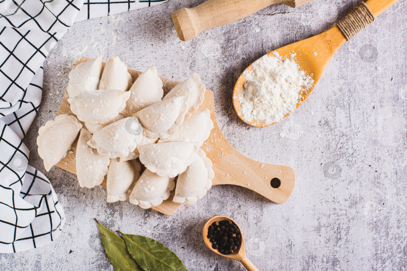 Скачать Домашние сырые пельмени с мясом на разделочной доске на столе вид сверху фотосток Ozero