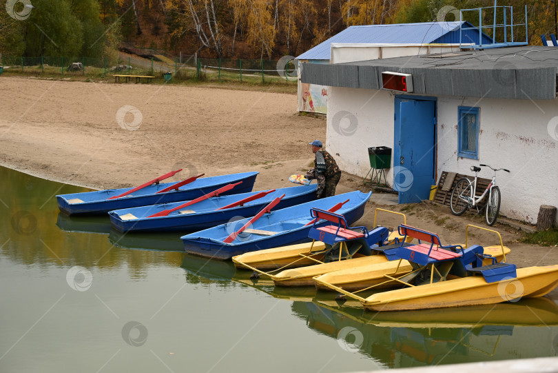 Скачать Осенний лес с лодкой. Отражение оранжевых и зеленых деревьев в озере. фотосток Ozero