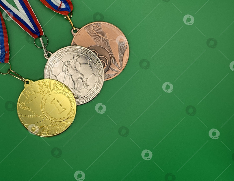Скачать Медали за первое, второе и третье место в спортивном соревновании. На зеленом фоне. фотосток Ozero