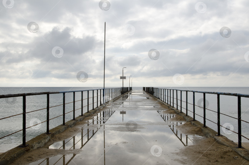 Скачать Морской пирс или причал после дождя на берегу Черного моря фотосток Ozero