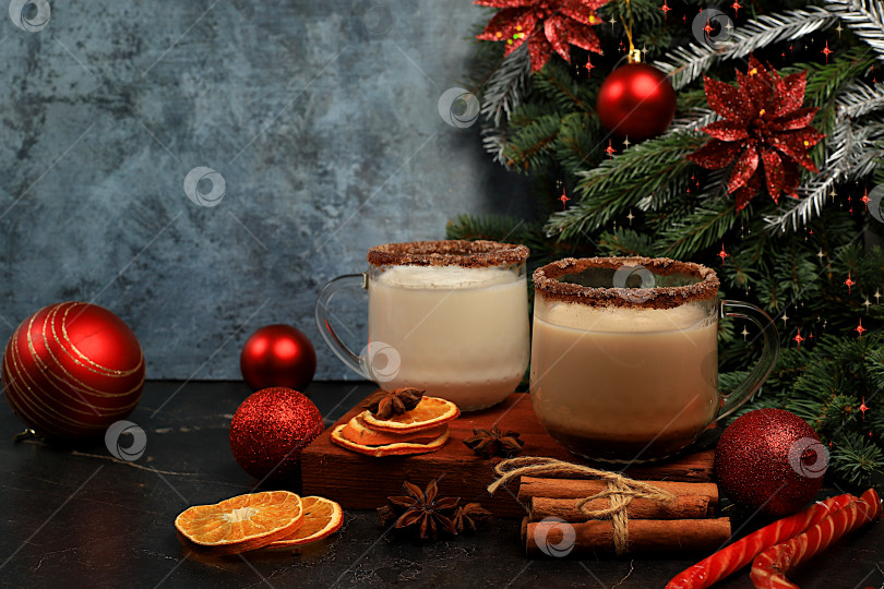 Скачать Гоголь-моголь с корицей, мускатным орехом и имбирем - молочный напиток для рождественских и зимних праздников на фоне еловых веток и украшений. Согревающий молочный напиток в холодное время года, праздничная композиция, фотосток Ozero