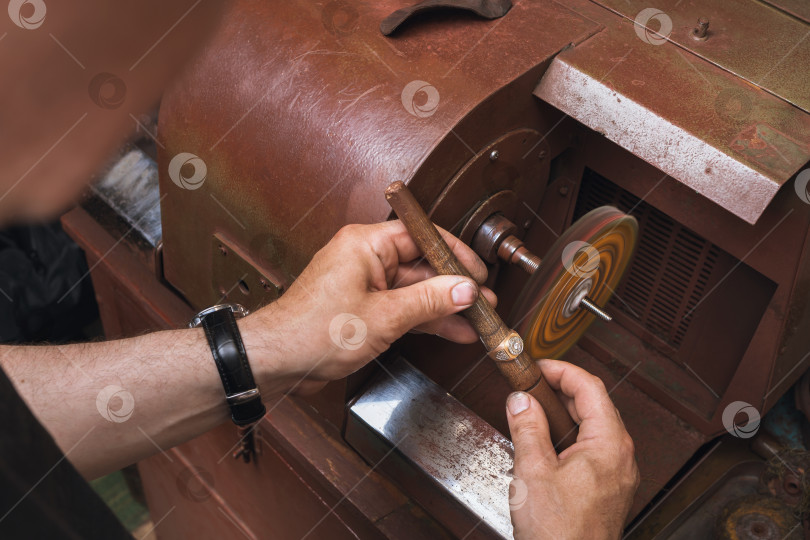 Скачать Ювелир полирует золотое кольцо на станке в мастерской, рабочий процесс фотосток Ozero