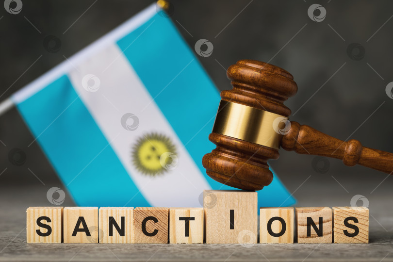 Скачать Судейский молоток, деревянные кубики с текстом на фоне аргентинского флага, концепция на тему санкций в Аргентине фотосток Ozero
