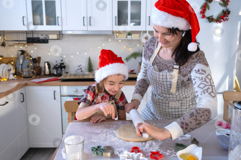 Скачать Мама и дочь на белой кухне готовят печенье к Рождеству и новому году. Семейный день, подготовка к празднику, учимся готовить вкусную выпечку, вырезаем фигурки из теста с помощью формочек фотосток Ozero