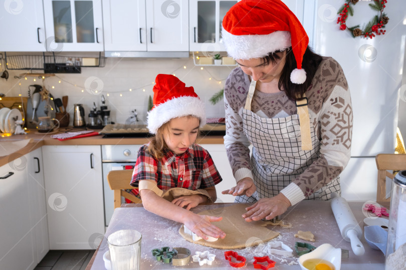 Скачать Мама и дочь на белой кухне готовят печенье к Рождеству и новому году. Семейный день, подготовка к празднику, учимся готовить вкусную выпечку, вырезаем фигурки из теста с помощью формочек фотосток Ozero