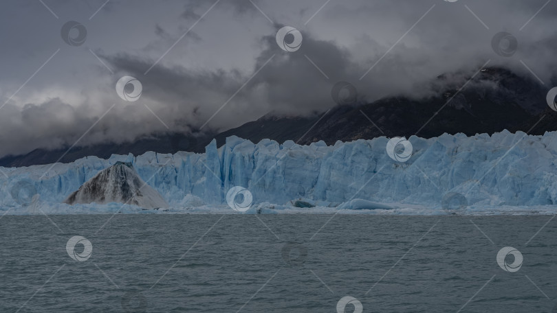 Скачать Стена голубого потрескавшегося льда возвышается над бирюзовым озером. фотосток Ozero
