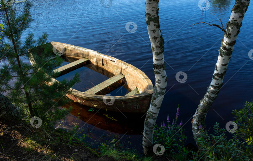 Скачать Маленькая погруженная в воду деревянная гребная лодка на спокойном озере фотосток Ozero