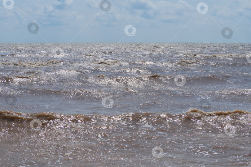 Скачать Пейзаж Азовского моря ветреным летним вечером. Вид на море с берега, темные волны с солнечными бликами. Блестящие волны на поверхности мутной воды, голубое небо с облаками, горизонт фотосток Ozero