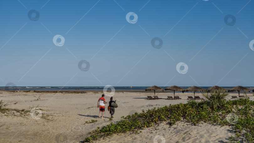 Скачать Мужчина и женщина идут по песчаному пляжу к океану. фотосток Ozero