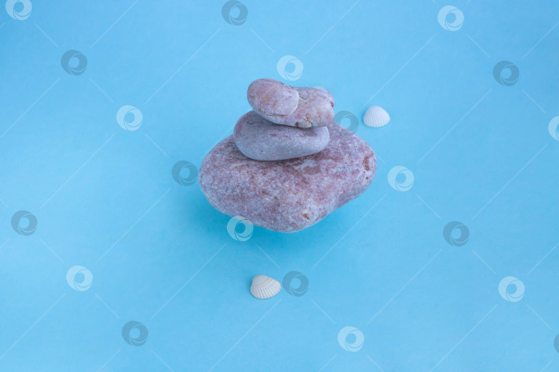 Скачать Стопка плавающих розовых камней и маленьких ракушек на голубом фоне. Концепция расслабляющего массажа для здоровья фотосток Ozero