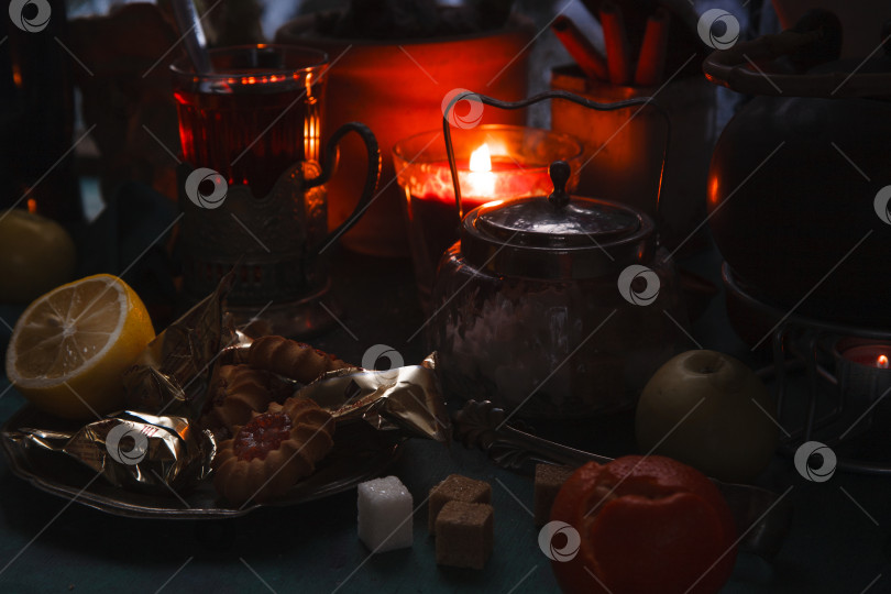 Скачать Натюрморт с чашкой чая, горящей свечой, фруктами и печеньем перед замерзшим зимним окном, концепция уютного вечера. фотосток Ozero