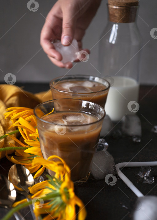 Скачать Кто-то кладет кусочек льда в стакан с кофе со льдом фотосток Ozero