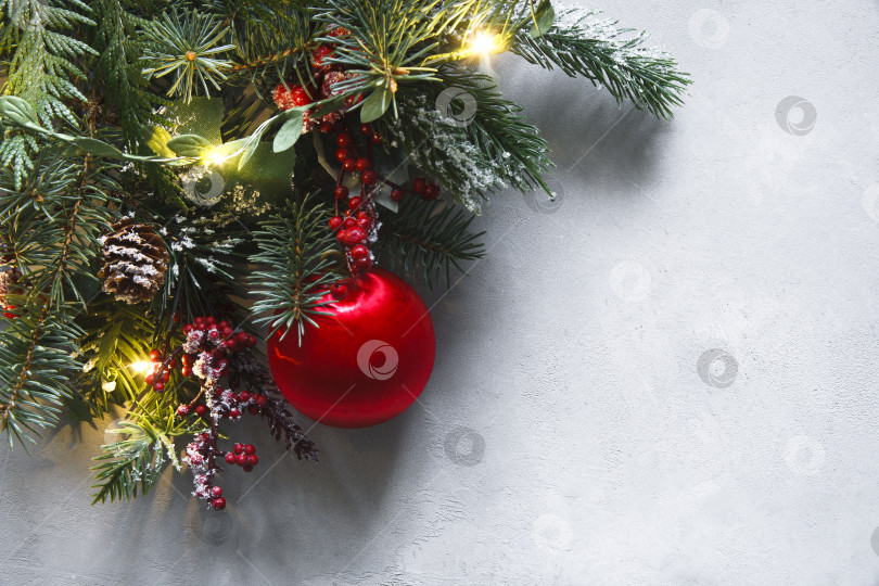 Скачать Рождественские обои, выполненные из еловых веток, красного воздушного шара, красных ягод, огней и минусов на сером фоне. Рождественские обои. фотосток Ozero