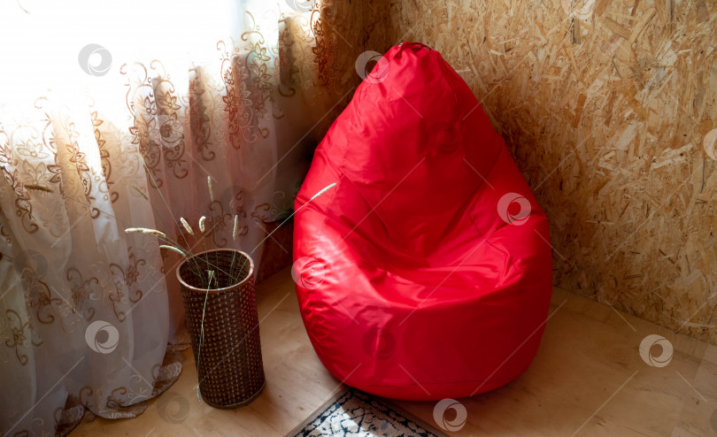 Скачать Современное уютное красное кресло в форме капли на деревянном фоне фотосток Ozero