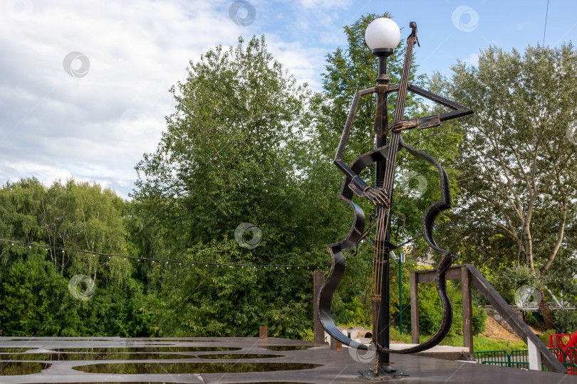 Скачать Кованый памятник-фонарь с виолончелью на городской площади фотосток Ozero