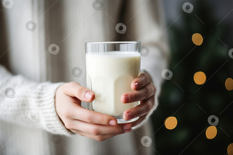 Скачать Концепция сухого января. Крупным планом женские руки, держащие стакан молока, на фоне рождественской елки в помещении фотосток Ozero