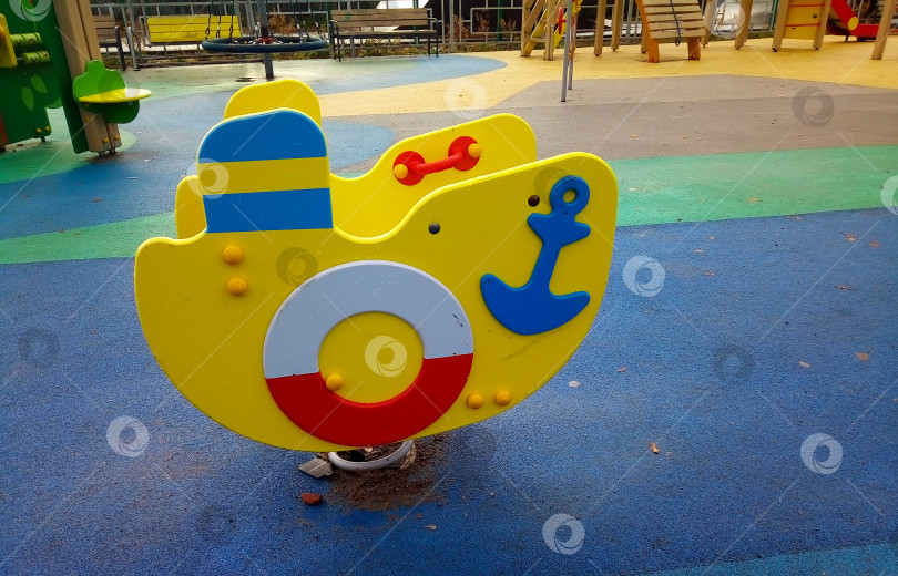 Скачать Деревянная желтая лодка на детской площадке с прорезиненным покрытием. Детские спортивные увлечения фотосток Ozero