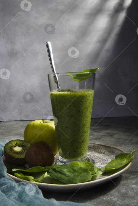 Скачать Высокий стакан свежего домашнего зеленого смузи с ингредиентами на зеленом столе. фотосток Ozero