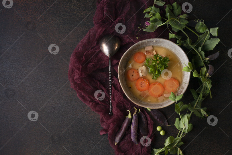 Скачать Свежий гороховый суп-пюре домашнего приготовления на темном фоне и фиолетовой скатерти в загородной кухне, ровный стол, сдержанный стиль фотосток Ozero