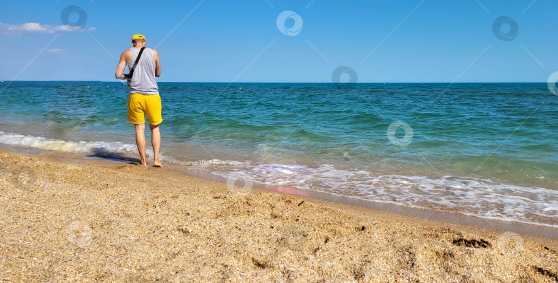 Скачать Мужчина стоит лицом к морю, в морских волнах на пляже. Концепция отдыха. Место для вашего текста фотосток Ozero