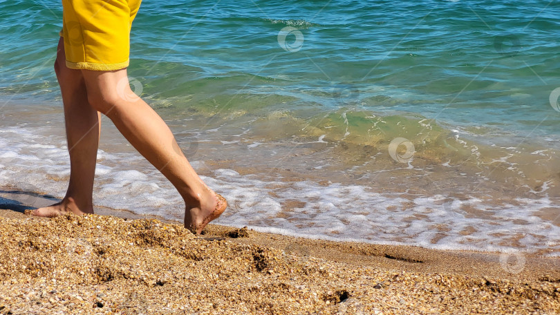 Скачать Загорелые ноги в морских волнах на пляже. Концепция отдыха. Место для вашего текста фотосток Ozero