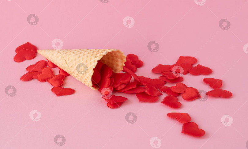 Скачать Креативная фотография пустых вафельных рожков с разбросанными красными сердечками на розовом фоне. Концепция любви, лета, весны фотосток Ozero