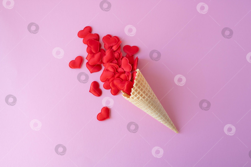 Скачать Креативная фотография пустых вафельных рожков с разбросанными красными сердечками на розовом фоне. Концепция любви, лета, весны фотосток Ozero