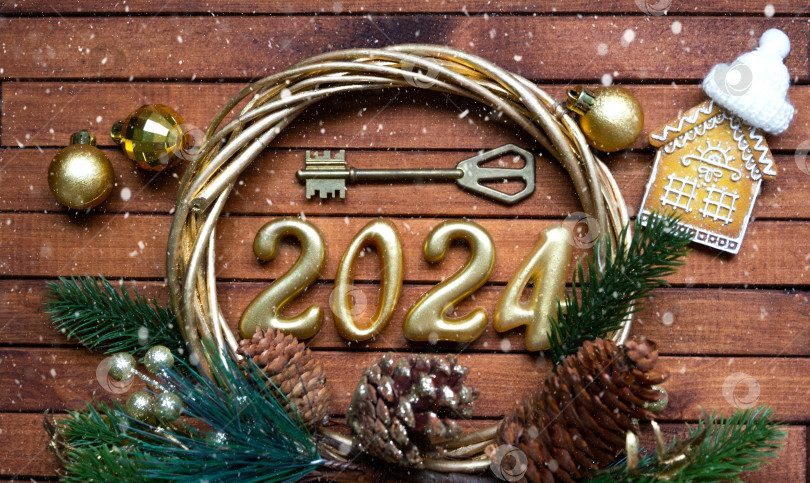 Скачать Ключ от дома с брелком коттедж на праздничном коричневом деревянном фоне со звездами, огоньками гирлянд. Деревянные буквы на Новый 2024 год, поздравительная открытка. Покупка, строительство, переезд, ипотека, страхование фотосток Ozero