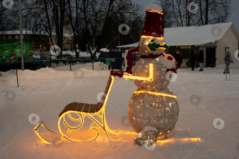Скачать В вечернем парке светящийся снеговик на зимних санях фотосток Ozero