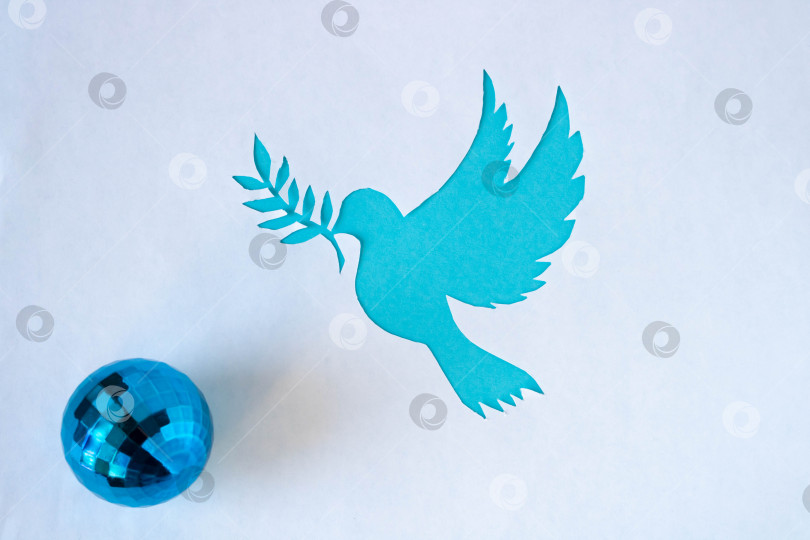 Скачать Трафарет голубя с веточкой, вырезанный из белой бумаги на синем фоне ко Всемирному дню мира. Всемирный день науки во имя мира и развития фотосток Ozero
