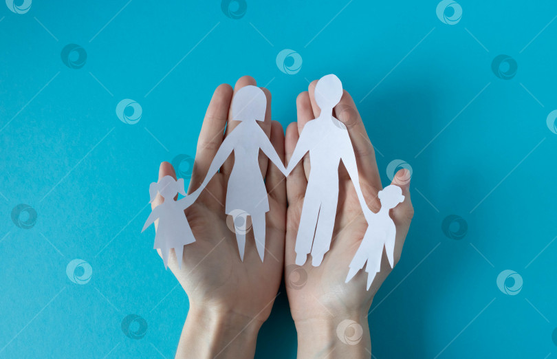 Скачать Руки держат бумажную семью на синем фоне. Концепция Дня семьи, Дня братьев и сестер, Дня прав человека, Дня мира во всем мире фотосток Ozero