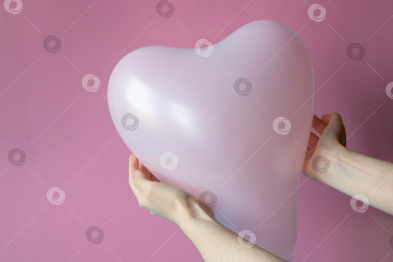 Скачать Женские руки держат розовый шар в форме сердца, выделенный на розовом фоне фотосток Ozero