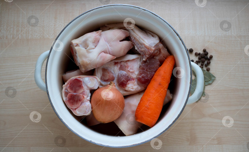 Скачать В старую эмалированную кастрюлю положите сырое свиное мясо и ножку, морковь и лук для приготовления желе фотосток Ozero